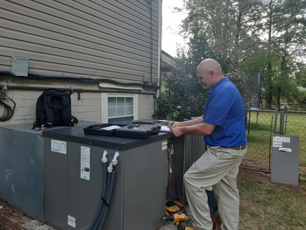 Air conditioner being repaired by technician in Alabama.